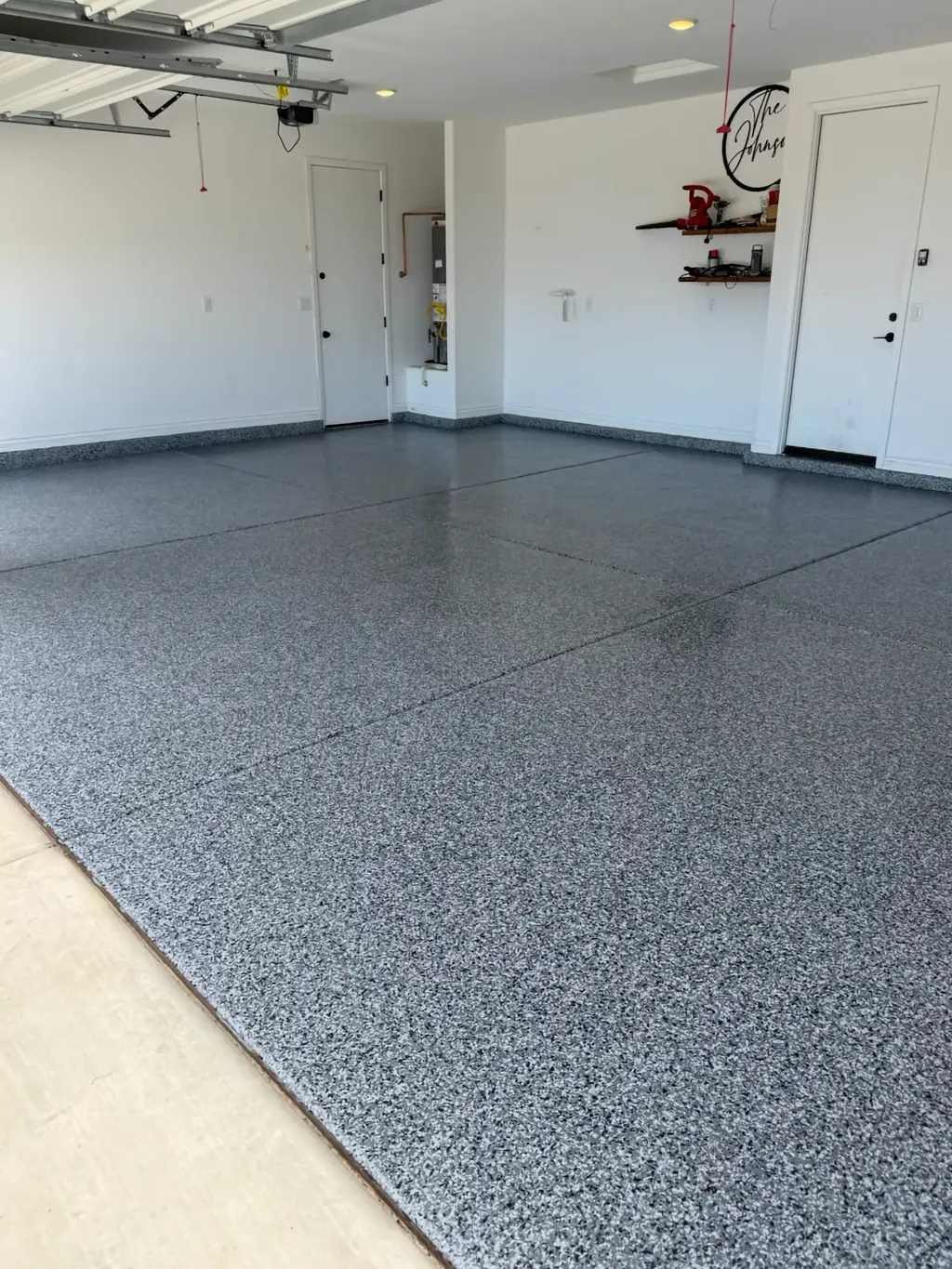 Finished two-car garage floor with a gray full-flake coating running wall to wall and up the base of the walls.