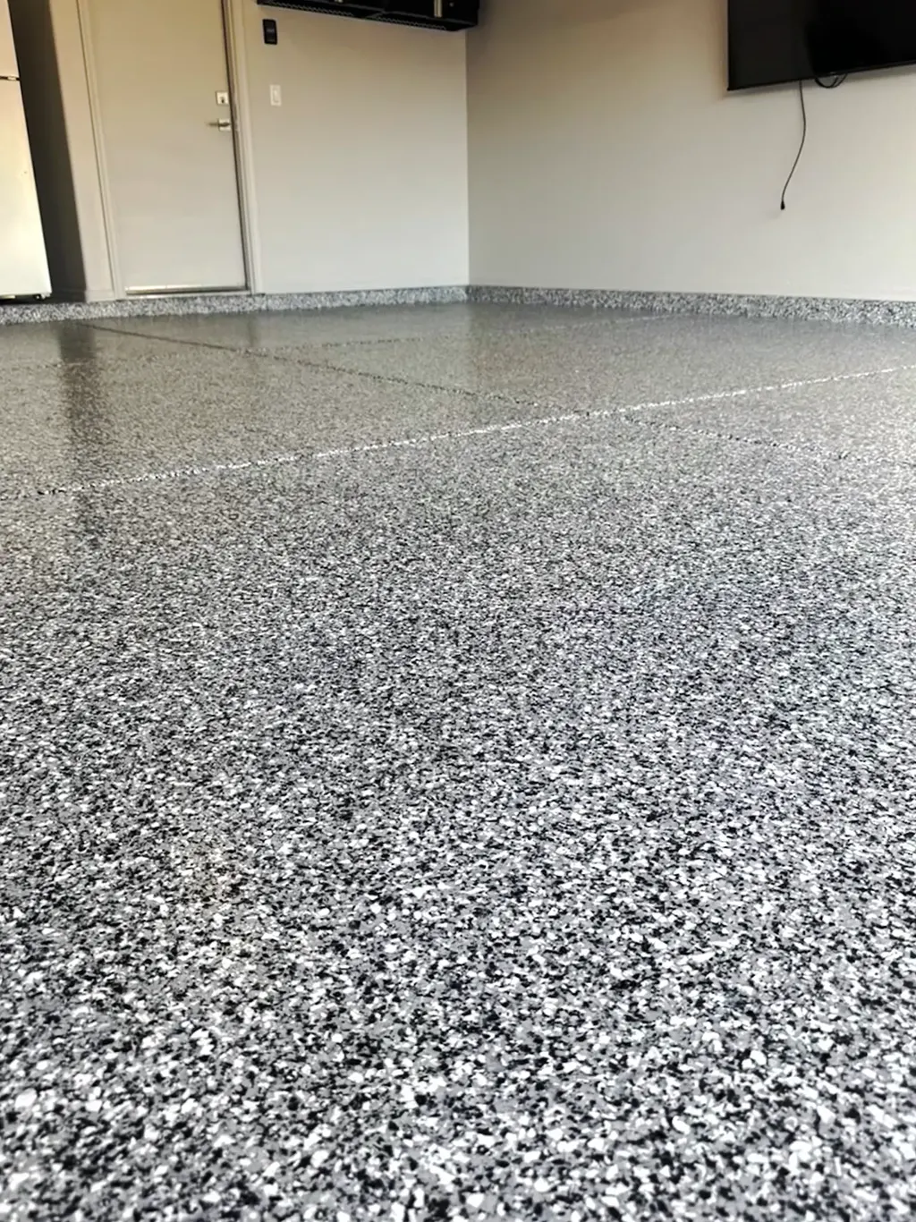 Close view of a white and gray flake garage floor coating showing flake density and sheen.