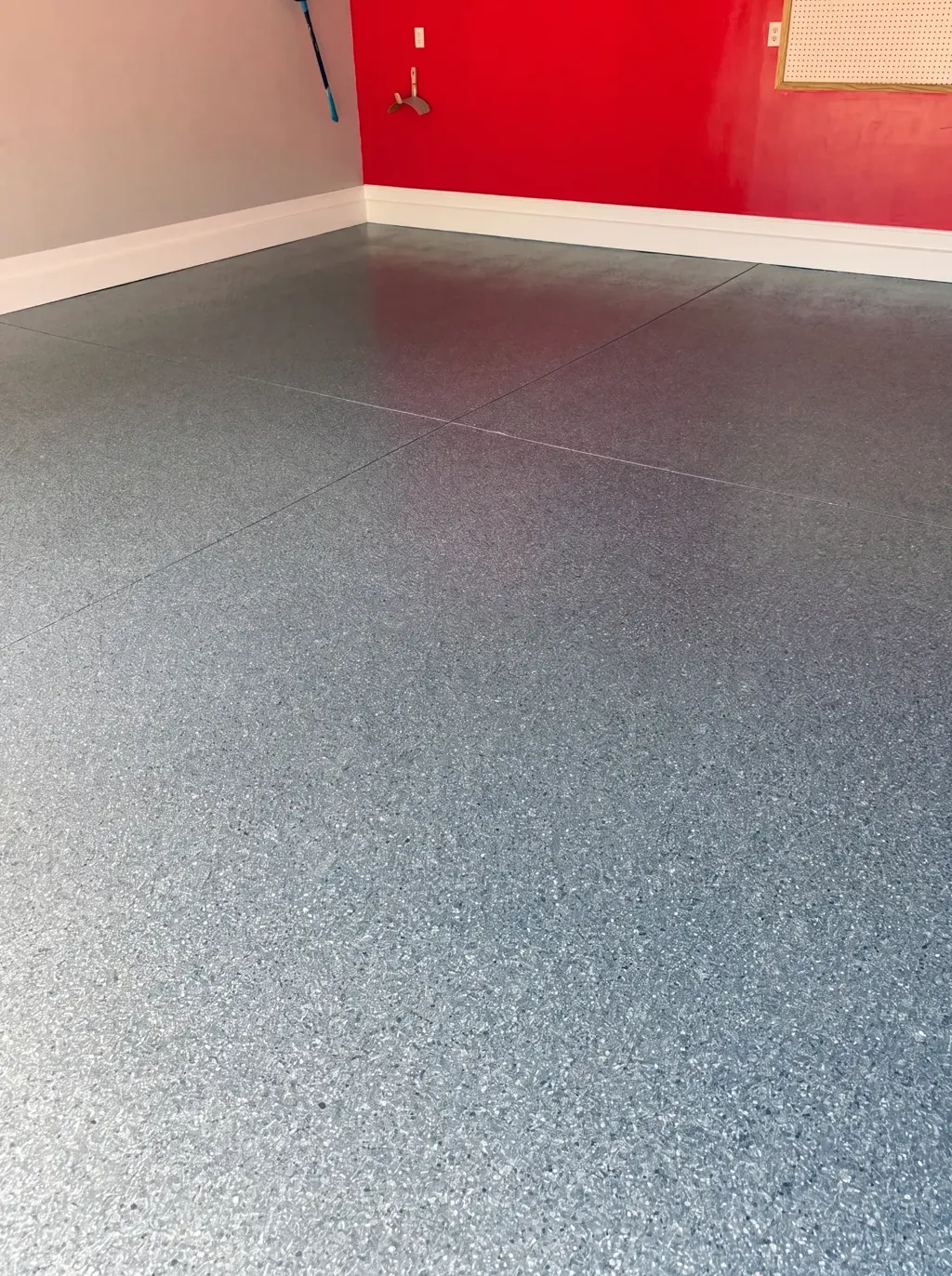 Finished garage floor with a blue and gray flake coating meeting a crisp red accent wall.