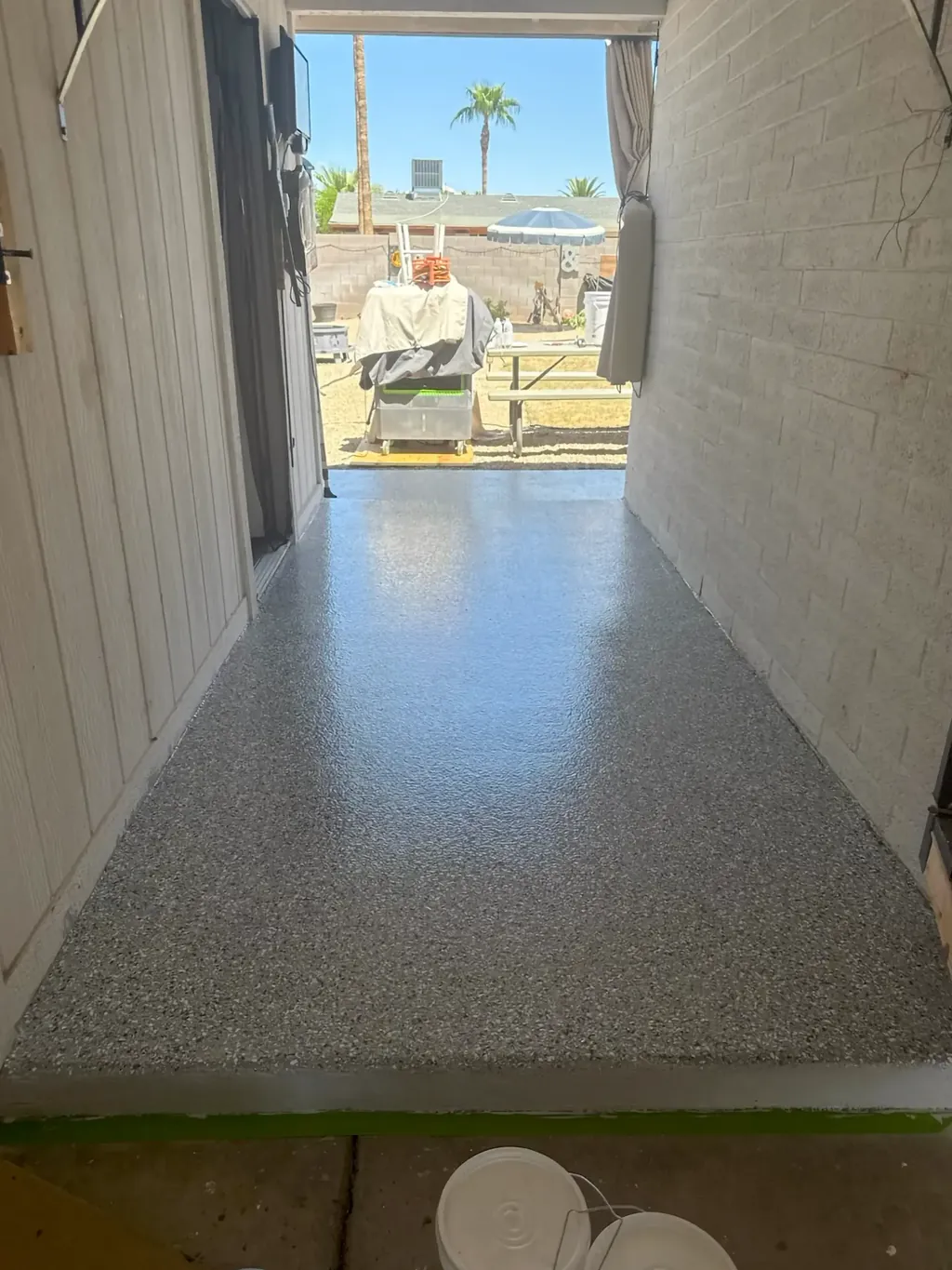 Coated concrete walkway between a garage and a backyard, showing an even flake finish and clean edges.