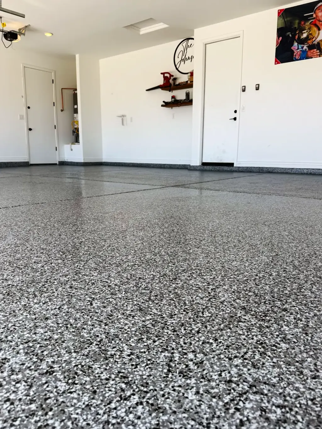 Low-angle view of a white and gray flake garage floor coating with a satin topcoat.