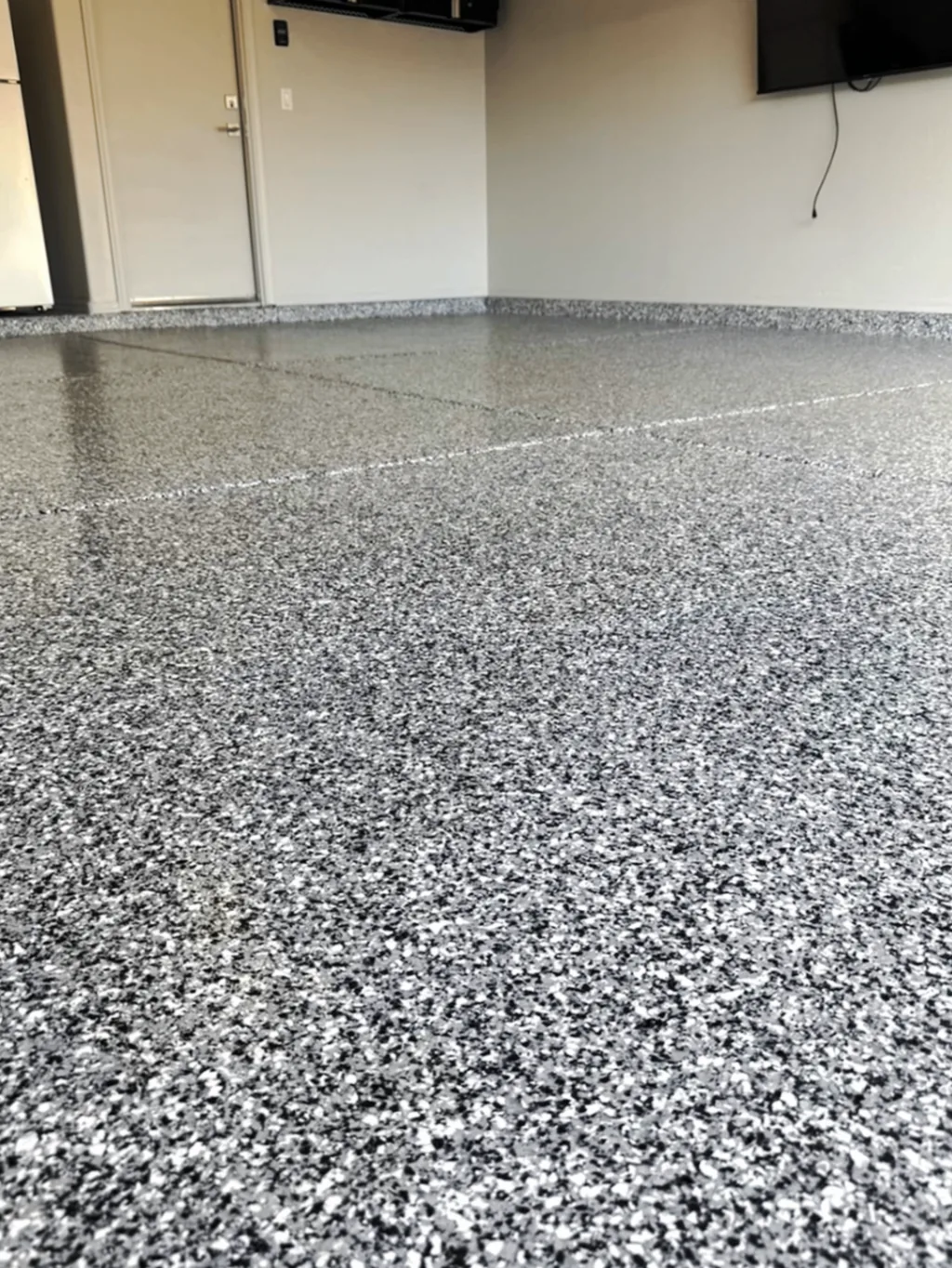 Low-angle close-up of a finished full-flake coating, used here to show the kind of uniform surface prep and finish detail required before a topcoat performs well.