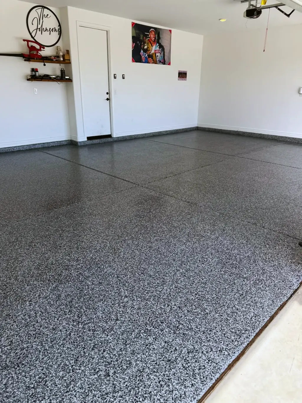 Coated garage floor in a white and gray flake blend, carried up onto the wall base.