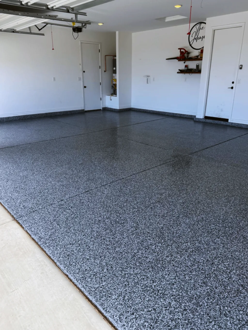 Finished garage floor coating viewed from the driveway with clear flake coverage across the slab.
