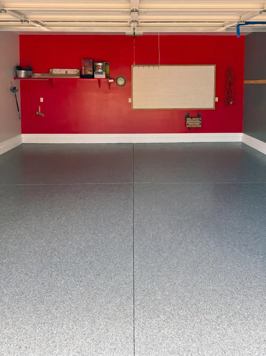 Wide view of a coated two-car garage with a blue-gray flake floor and red accent wall.