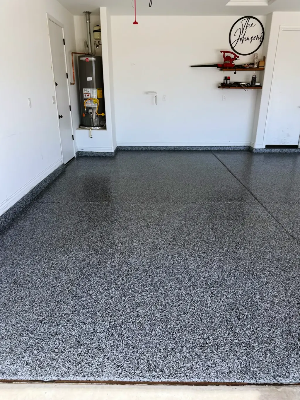 Finished white and gray flake garage floor running wall to wall around a water heater alcove.